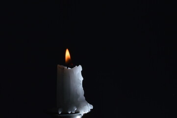 Burning Candle with Melting Wax on Black Background &ndash; Warm Glow and Dramatic Lighting in Minimalist Still Life Photography