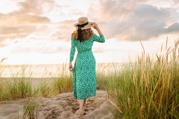 Happy woman  walking in the beach near tall grass. Flying hairs. Outdoor. Fashion style