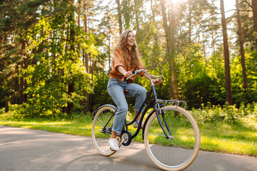 Young modern woman rides bicycle in the park. Sports activities. Taking care of environment © maxbelchenko