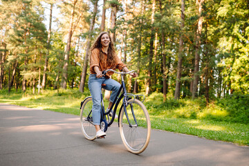 Young modern woman rides bicycle in the park. Sports activities. Taking care of environment