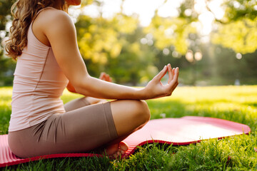 Morning yoga. Young beautiful woman  in sportswear stretching body on fitness mat at public park,...