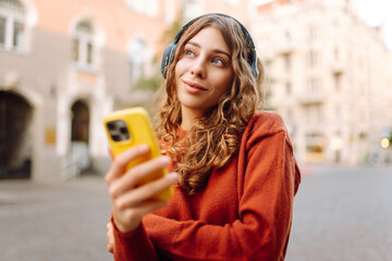 Young woman listening music while walking in the street. Travel, tourism, technology, blogging concept