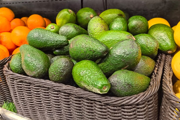 Fresh avocados stacked beautifully in a basket at a bustling market
