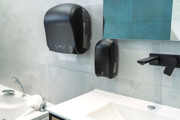 Black auto cut dispenser for hand towels and  black dispenser for the liquid soap in the beautiful toilet.