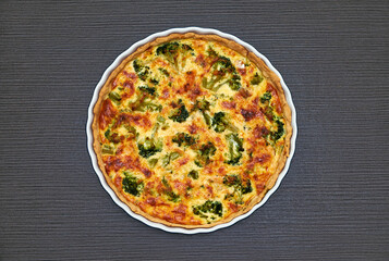 Delicious homemade broccoli quiche with golden crust and melted cheese in a white ceramic dish.