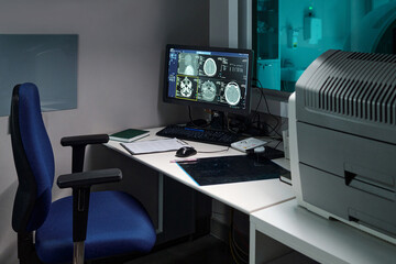 Office setting featuring high-tech equipment and multiple computer monitors displaying imaging data. Focus on organization and use of advanced technology tools and devices