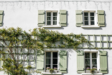 House with white walls and green window shutters, and green ivy on the house. Beautiful house for rent in a Polish city near the mountains, Janice, Poland.