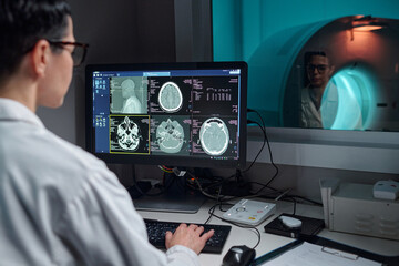 Professional medical technician analyzing brain scans on high-tech device in diagnostic lab. Image...