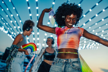 Young woman dancing with friends at music festival under string lights