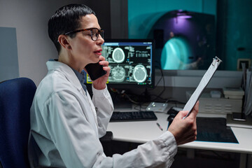 Medical professional in white lab coat analyzing diagnostic imaging report with MRI scans displayed...