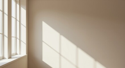 Fototapeta premium Natural light filtering through large windows casting soft shadows on a beige wall, creating a serene and tranquil atmosphere in a bright space