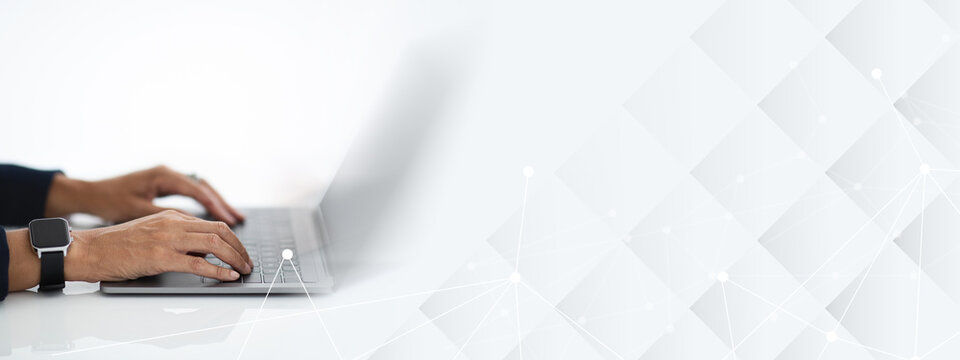 Unrecognizable mature woman with smart watch on her hand wearing formal outfit sitting at workdesk at office, typing on computer laptop keyboard, white background, blank screen, cropped
