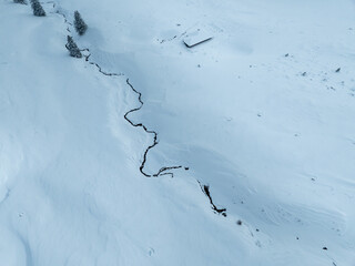 Aerial view of meandering through snowy landscape in Switzerland.