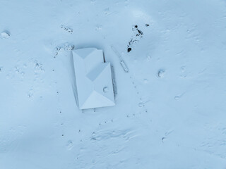 Aerial view of mountain cottage in snow covered landscape.