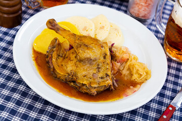 Juicy roasted duck leg served with red and white cabbage and Czech dumplings on plate