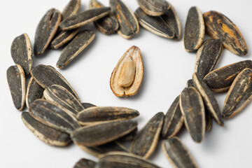 Sunflower seeds forming a circle around an opened one on white background