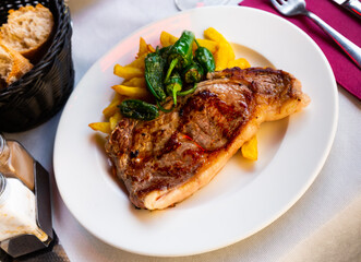 Appetizing beef entrecote with french fries and stewed bell peppers served at plate