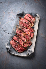 Traditional barbecue dry aged Wagyu rib eye beef steak with salt and pepper sliced and served as close-up on a design plate