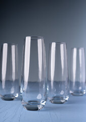 sleek glass cylinders with reflective transparency on blue surface in soft gradients and minimalist composition evoking elegance and simplicity, artistic, linear, shine, glassware, purity