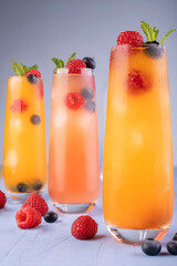 refreshing berry-infused beverages in tall glasses with mint garnish on light surface, highlighting...