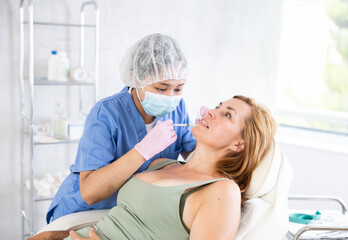 Portrait of Asian doctor giving injection to woman lying on couch