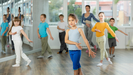 During dance workshop, girl with team of young like-minded children learn to dance hip hop dances,...