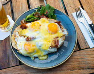Scrambled eggs with bacon served on plate with greens. Uitsmijter, Netherlands dish