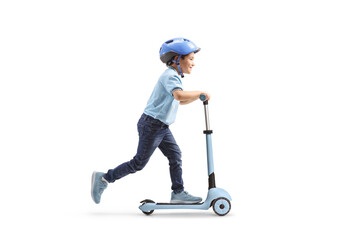 Full length profile shot of a boy with a helmet riding a push scooter