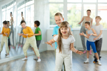 Obraz premium Group of children training movements of twist in dance studio with female tutor