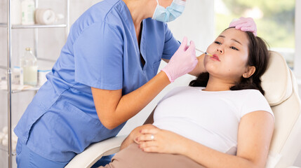 Obraz premium Skilled cosmetologist performing procedure for injecting beauty injections for the patient