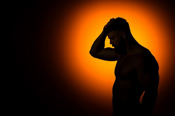 Silhouetted man in deep contemplation against a dramatic glowing background
