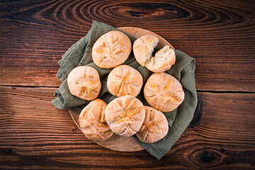 Freshly baked Kaiser rolls offered as top view on a rustic wooden tray with copy space