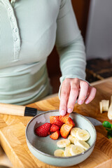 Young girl picking a strawberry from the fruit bowl, healthy eating at home.