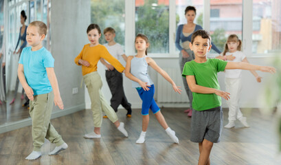 Obraz premium Active preteen boy practicing sport dances with other children and teacher during dancing classes
