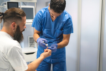 Doctor measuring patient's blood glucose level with glucometer in hospital room