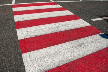 Red and white crosswalks to increase visibility. A universal urban symbol of mobility and road safety, crosswalks connect opposing sidewalks in cities around the world. road symbols on asphalt