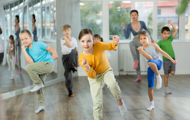 Dynamic little girl training Rock-and-Roll dance poses with instructor and other attendees of...
