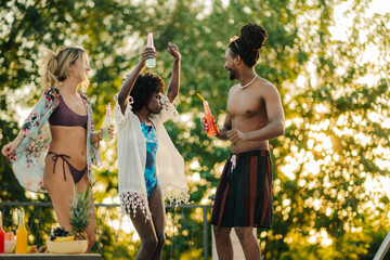 Friends dancing at pool party, enjoying summer cocktails and celebrating friendship