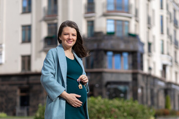 beautiful young pregnant woman with keys to house, apartment outdoors. purchase of real estate. maternity capital. female owner of new flat, home . mortgage, real estate installment plan.