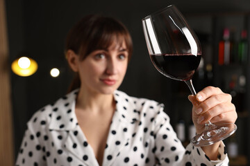 Professional sommelier analyzing quality of red wine indoors, selective focus