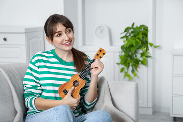 Happy woman playing ukulele on sofa at home