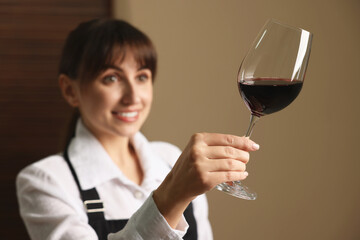 Professional sommelier analyzing quality of red wine indoors, selective focus