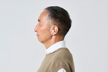 Fototapeta premium ワイヤレスイヤホンを使う私服姿のシニア男性