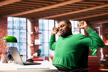Person in home office stretching back after sitting at desk too long. Freelancer in living room...
