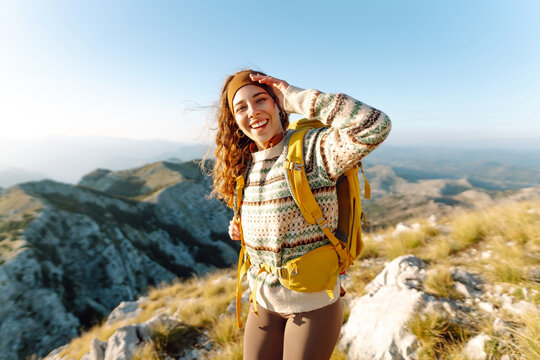Woman tourist traveler walking on the top of mountain in summer sunny day under sun light. Beautiful mountains landscape view. Adventure active