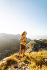 Woman tourist traveler walking on the top of mountain in summer sunny day under sun light....