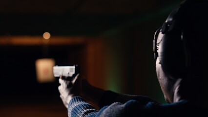 Person wearing safety glasses loading pistol ammo magazine during firearm practice session at shooting range. Close up of BIPOC man reloading gun, learning self defense, pointing weapon
