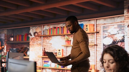 Startup employee coming at work with notebook, conducting code review to fix bugs, identifying...