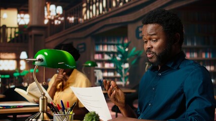 African american college student feels frustrated and overwhelmed with the learning struggles, worried depressed pupil struggling to memorize information from class notes. Camera A.