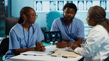 Team of male and female african american medical staff discussing diagnostic results with a medic...